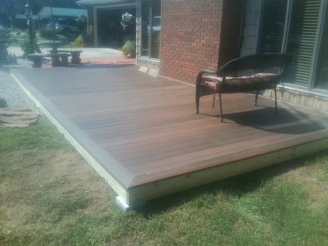 New wood deck and wicker chair beside a brick house in Cumberland